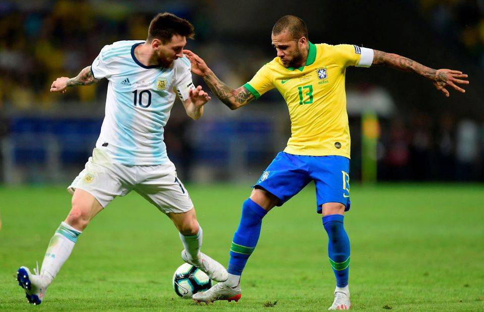 Dani Alves of Brazil tackles Argentina captain Lionel Messi in the Copa America final