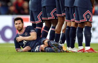 PSG attacker Lionel Messi lying down behind the wall