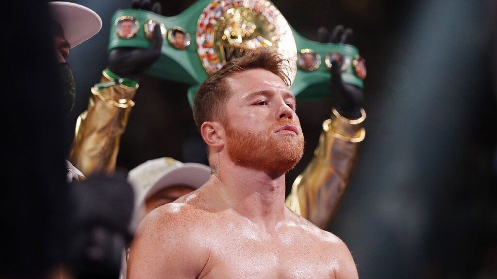Canelo Alvarez in the boxing ring with his title being held up behind him