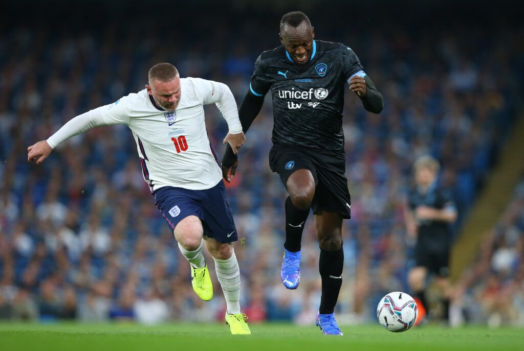 Usain Bolt of Soccer Aid World XI holds off a challenge from Wayne Rooney of England during Soccer Aid for Unicef 2021 match between England and Soccer Aid World XI at Etihad Stadium on September 04, 2021 in Manchester, England.