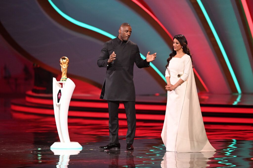Idris Elba and Reshmin Chowdhury are seen on stage with the Fifa World Cup Trophy during the FIFA World Cup Qatar 2022 Final Draw at the Doha Exhibition Center on April 01, 2022 in Doha, Qatar