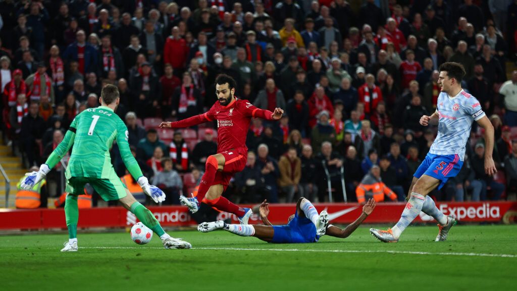 Mohamed Salah of Liverpool has a shot on goal whilst under pressure from Aaron Wan-Bissaka and Harry Maguire of Manchester United during the Premier League match between Liverpool and Manchester United at Anfield on April 19, 2022 in Liverpool, England.