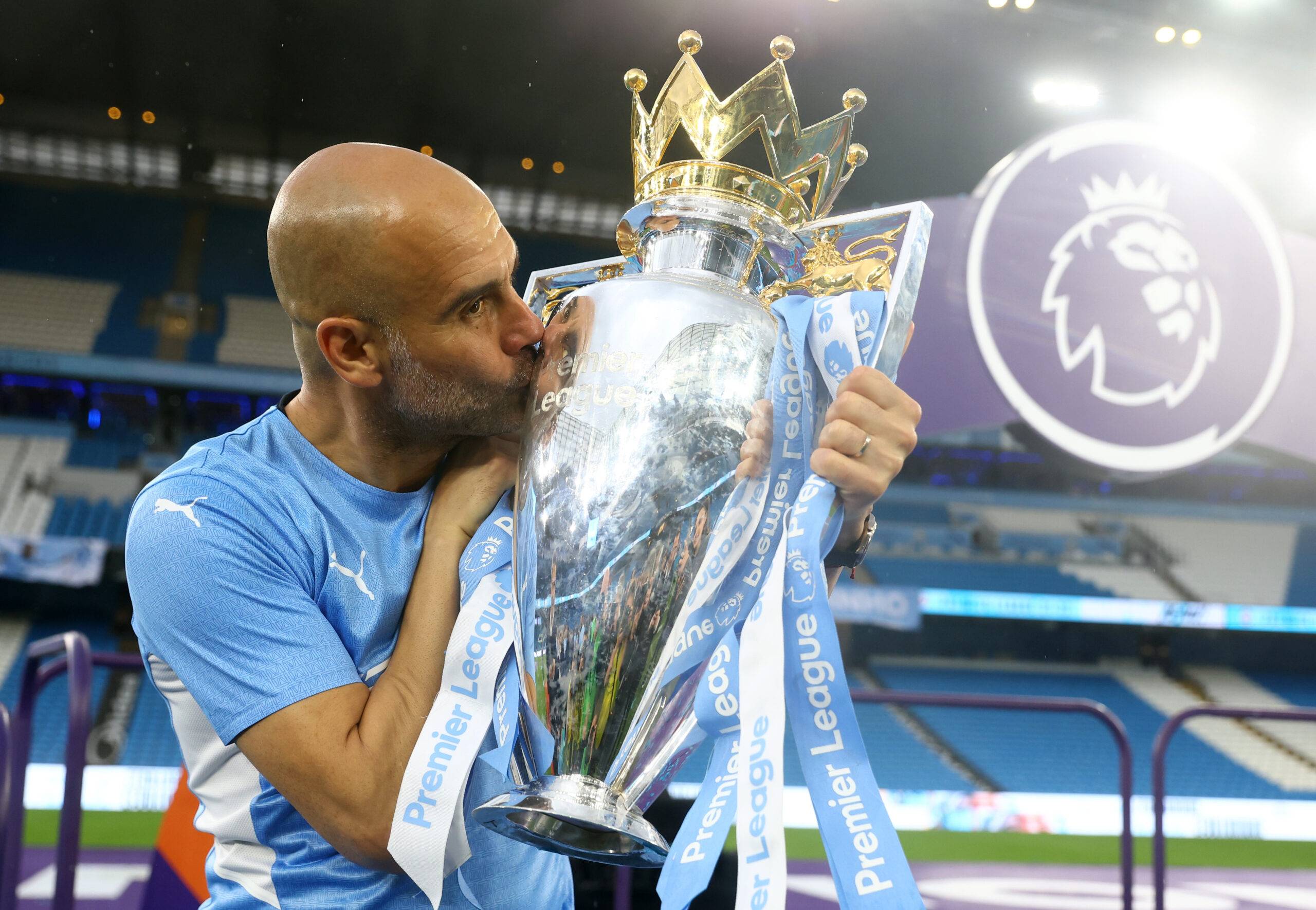 Guardiola kisses the Premier League trophy.