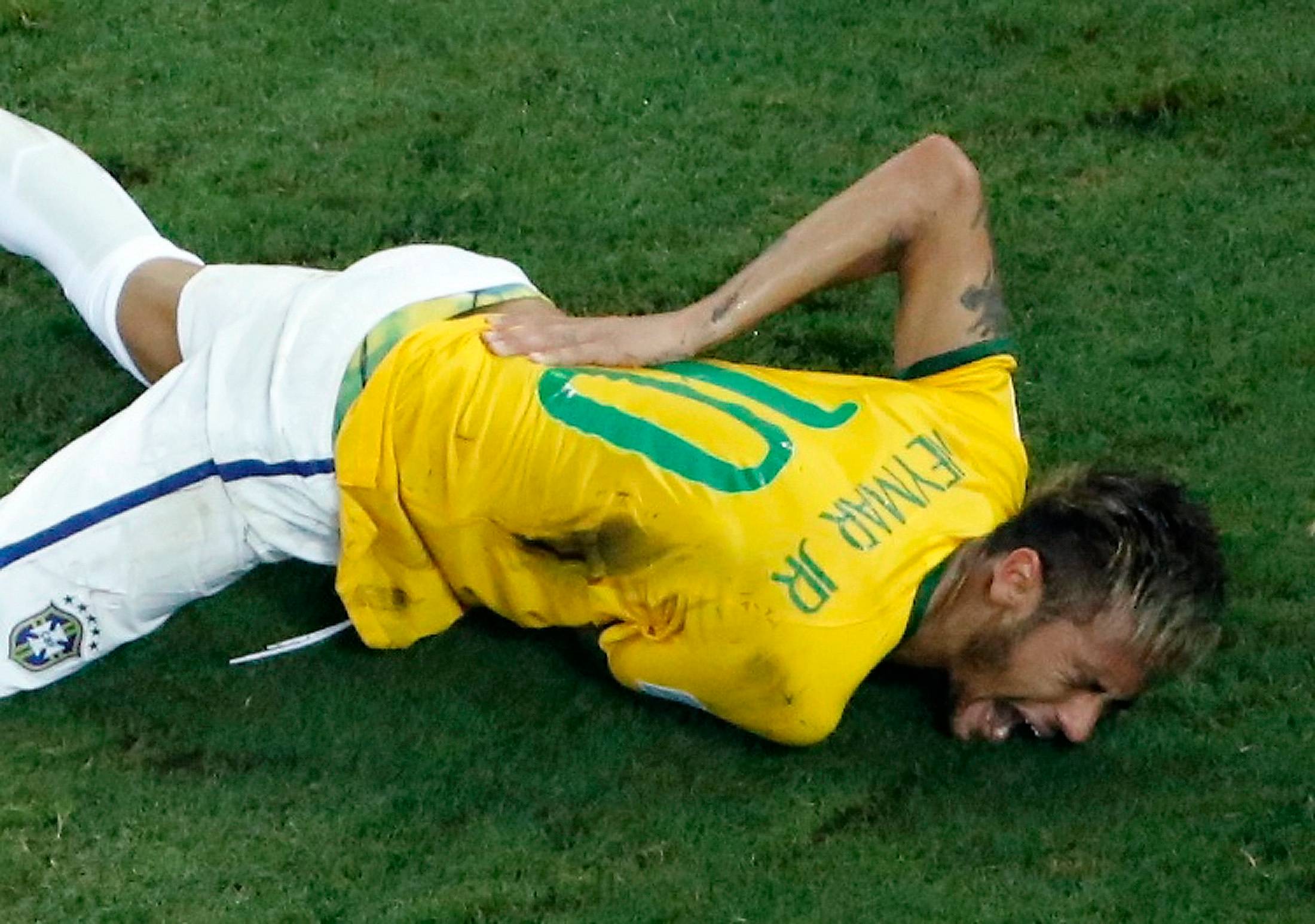 Brazil's Neymar holds his back in pain.